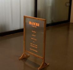 a wooden sign sitting on top of a floor next to a metal wall mounted clock