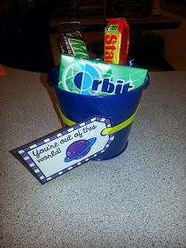 a blue bucket filled with candy on top of a counter next to a sign that says orbit