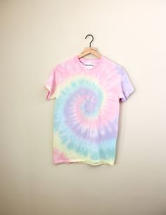 a t - shirt hanging on a wall with a tie dye design in the middle