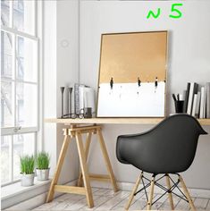 a black chair sitting in front of a wooden desk next to a white wall and window