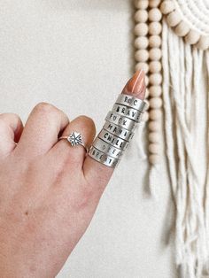 a woman's hand holding a stack of rings with letters on them and a star in the middle