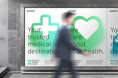 a man walking past a medical advertisement on the side of a building in front of stairs