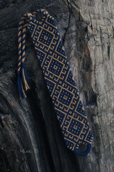 a blue and gold beaded tie sitting on top of a tree stump in the woods