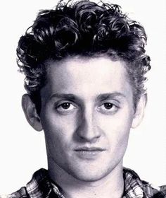 a young man with curly hair is posing for a black and white photo while wearing a plaid shirt