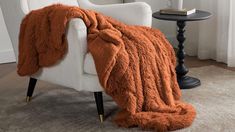 a white chair with an orange blanket on it