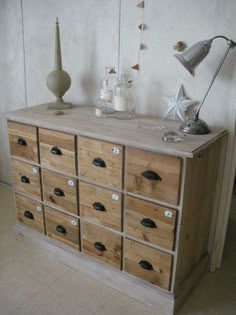 a wooden dresser with many drawers on it and a lamp in the corner next to it