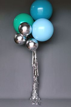 a bunch of blue and green balloons on a silver stick with some tassels