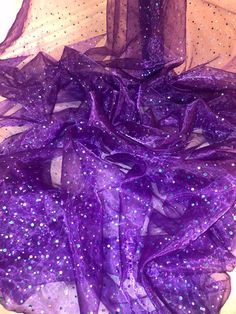 purple sequins and sheer fabric on a bed