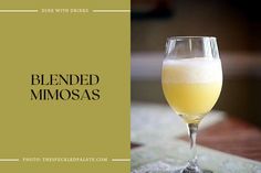 a glass filled with yellow liquid sitting on top of a table next to a napkin