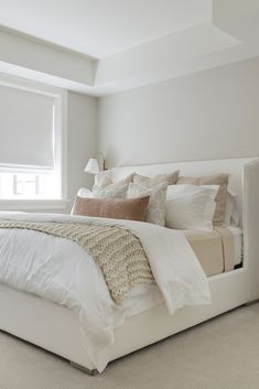 a white bed sitting under a window in a bedroom