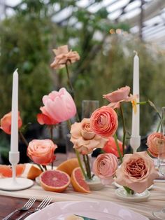 the table is set with flowers, candles and grapefruits in vases