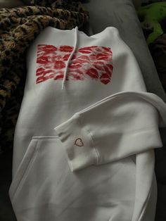 a white hoodie with red print on the front and chest, sitting next to other items