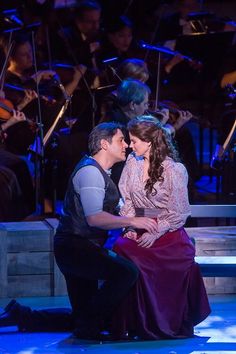 a man kneeling down next to a woman on stage