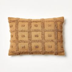 a brown pillow with squares on the front and back, sitting on a white surface