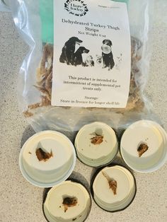 four white plates with food on them sitting next to a bag of dog treat treats