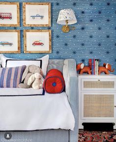 a bed with pillows and stuffed animals on it in a room decorated with blue wallpaper