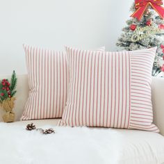 two red and white striped pillows sitting on top of a couch next to a christmas tree