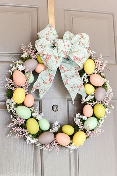 an easter wreath with eggs and flowers hanging on the front door to welcome guests into the home