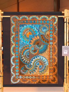 a blue and brown quilt hanging on a wall