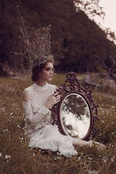 a woman sitting on the ground in front of a mirror