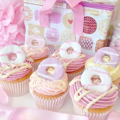 cupcakes with pink frosting and white icing in front of a gift bag