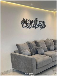 a living room with couches and arabic writing on the wall above it in black metal