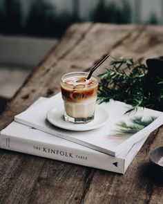 two books and a drink are sitting on top of a table next to each other