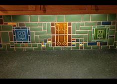 a kitchen counter with green and blue tiles on the backsplash, which is decorated with decorative designs