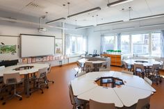 an empty classroom with desks and chairs in front of a projector screen on the wall