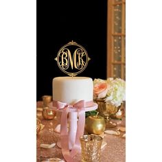 a wedding cake with a monogrammed initials on top and pink ribbon tied around it