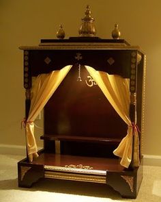 an ornate wooden cabinet with curtains on top