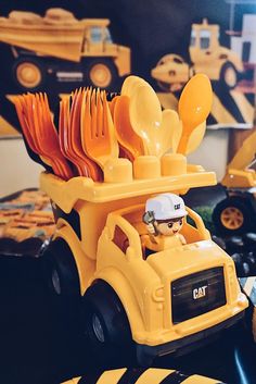 a yellow toy truck with utensils in the back