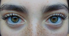 a close up of a person's eyes with freckles on their eyelashes