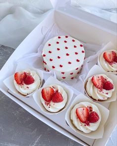 a box filled with cupcakes covered in white frosting and topped with strawberries