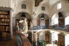 an old library with statues and bookshelves