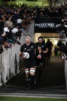 the rugby players are walking down the tunnel with their balls in hand and confetti thrown around them