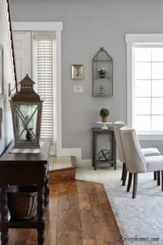 a living room filled with furniture and a lamp on top of a hard wood floor