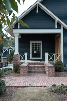 a blue house with brick steps leading up to the front door and entryway area