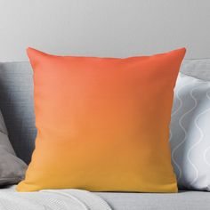 an orange and yellow ombreed throw pillow sitting on a couch with two pillows