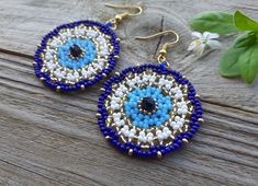 a pair of blue and white beaded earrings sitting on top of a wooden table