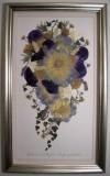 a framed painting with flowers on it in a silver and white frame hanging on a wall