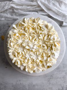 a cake with white frosting and flowers on it sitting on a plate next to napkins