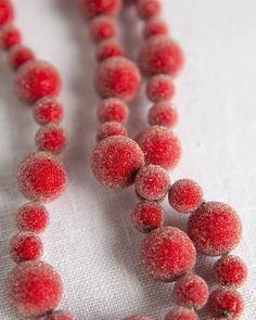 the beads are covered in frosting and sitting on a white tablecloth with a small red object hanging from it's center