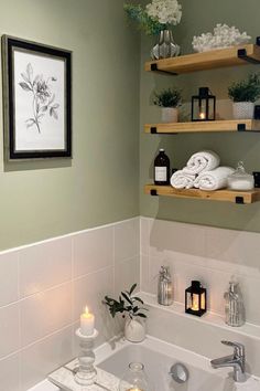 a white bath tub sitting next to a wall mounted shelf filled with candles and towels