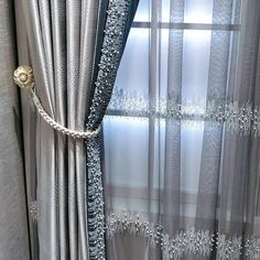 a curtain with beading on it next to a window in front of a curtain