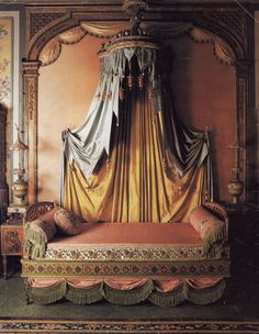 an ornate canopy bed with gold drapes