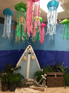 some jellyfish are hanging from the ceiling in front of a blue and green wall