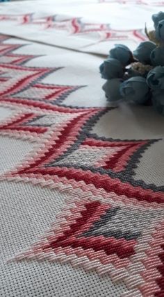 a close up of a rug with flowers on the ground next to some blue berries