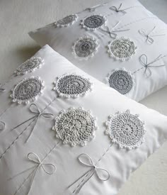 two white pillows with crocheted designs on them