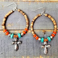 two pairs of earrings with beads and charms on top of a wooden table next to each other